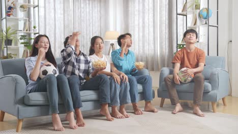 아시안 십대들이 tv에서 축구 경기를 응원하고 지켜보고 집에서 실망합니다.