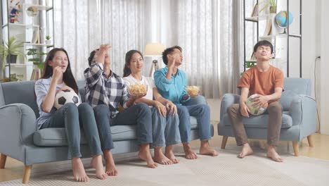 asian teenagers cheering and watching football game on tv and disappointed at home