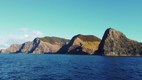 vista lejana del faro de cabo brett en una isla montañosa exuberante en nueva zelanda - plano general, cámara lenta