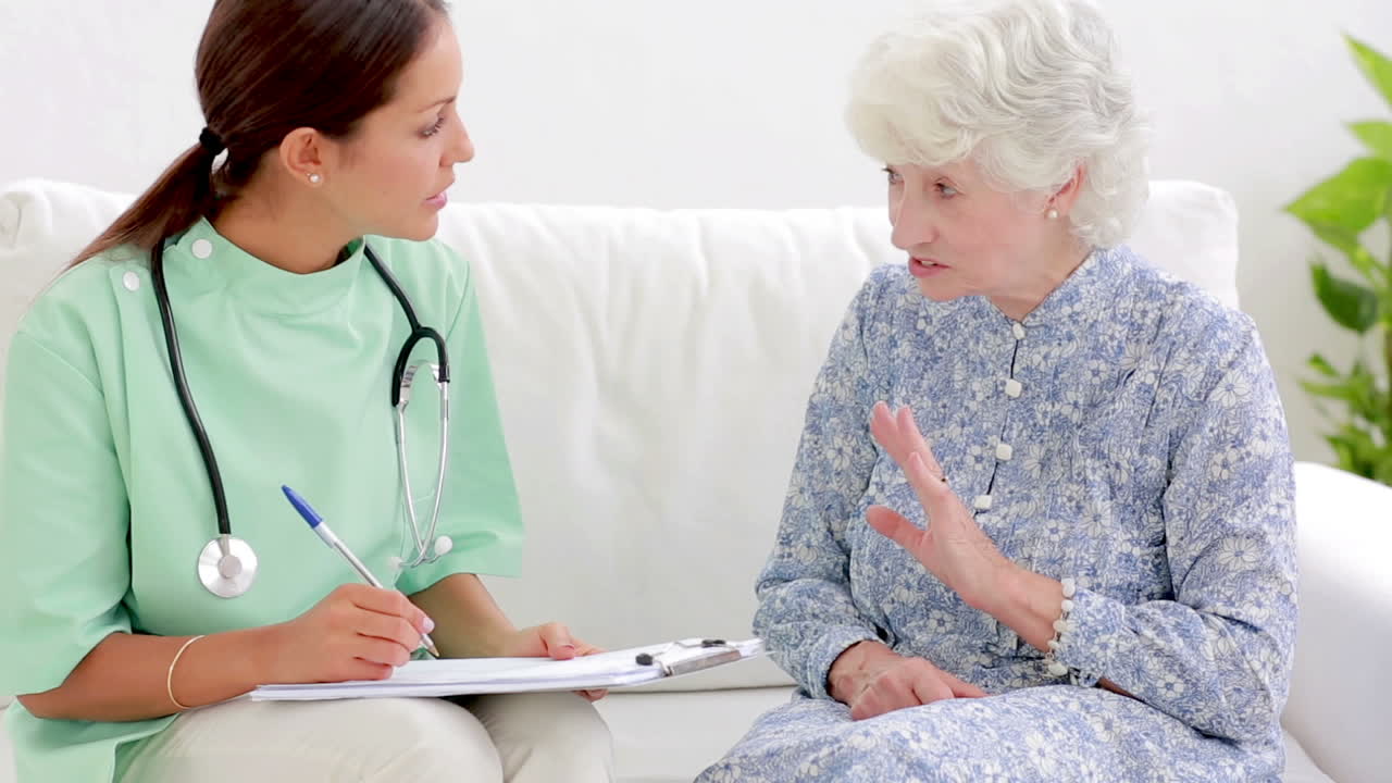 Elderly woman telling home nurse about back pain