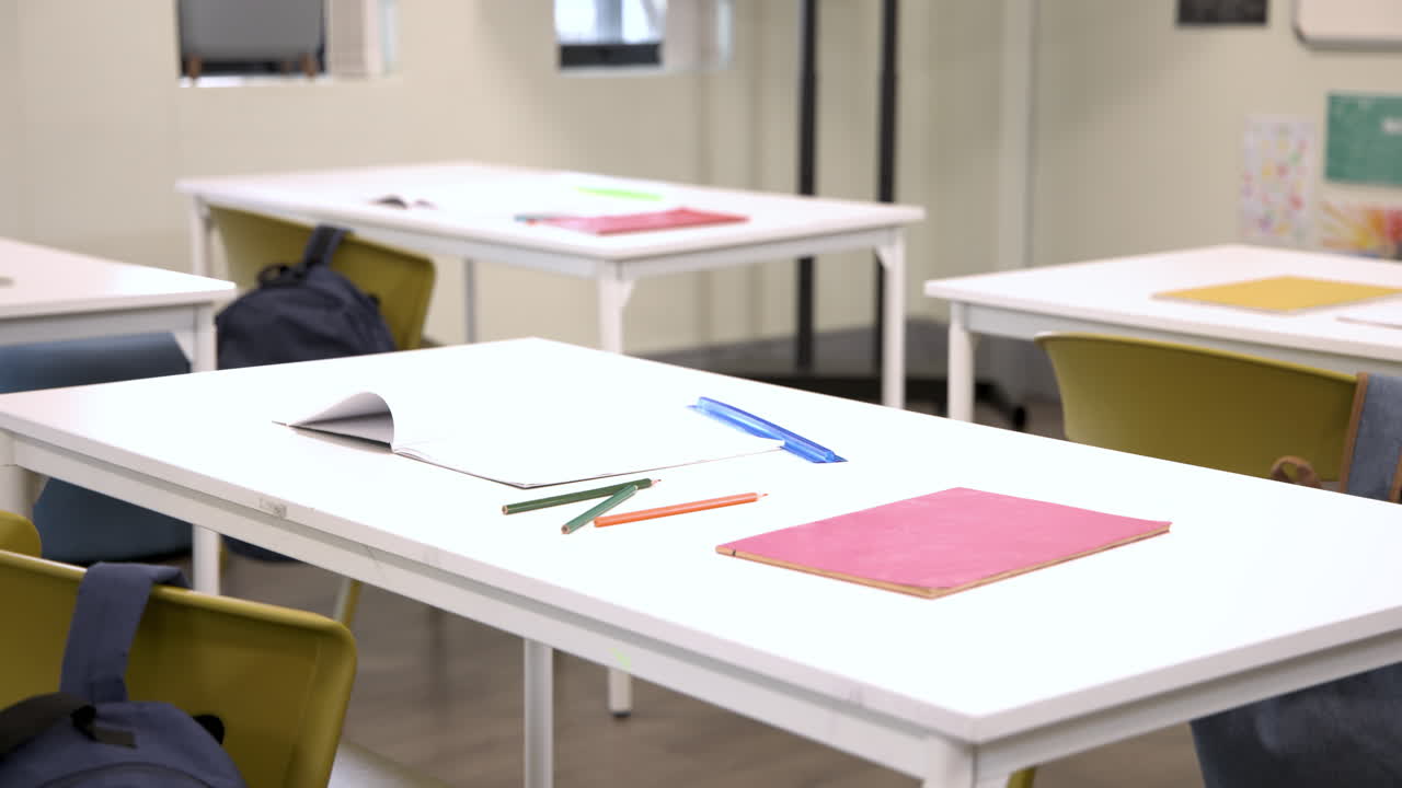 Empty classroom with desks, notebooks, and pencils ready for students