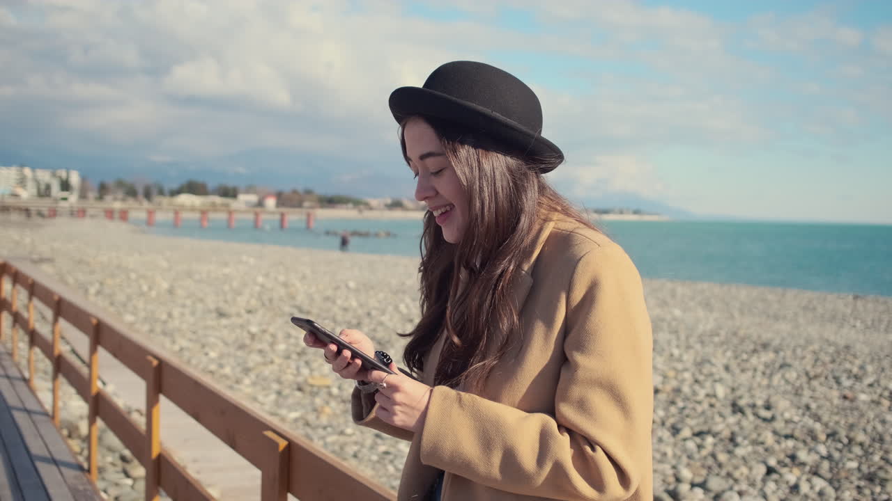 mujer usando el teléfono en un muelle de la playa