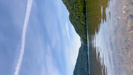 Serene-lake-in-Argentinian-Patagonia-with-clear-water-and-lush-green-hills,-vertical-shot,-timelapse