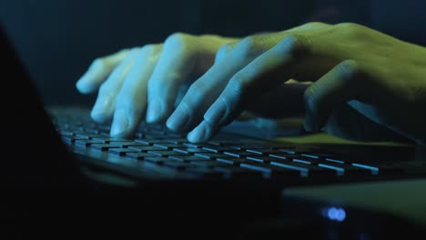 hands of a female hacker typing on laptop keyboard at night. close up