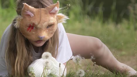 girl with cat mask playing with dandelions