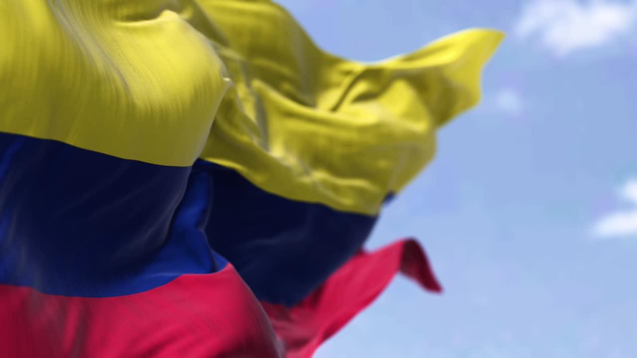 un primer plano detallado de la bandera nacional de colombia ondeando en el viento en un día despejado