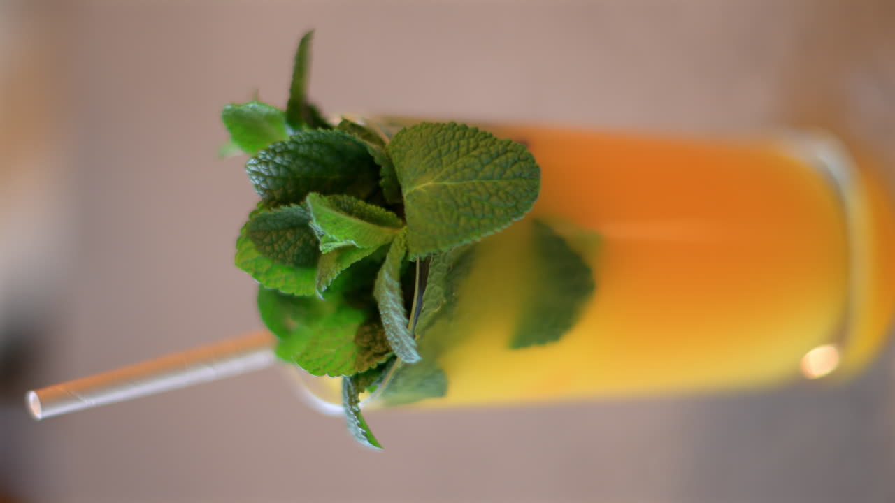 Fresh orange lemonade with mint leaves and paper straw