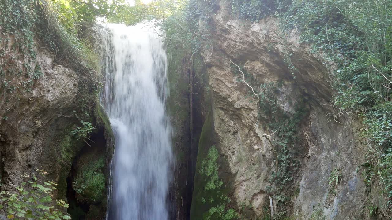 cascada rápida en cascada entre formación rocosa salpicando follaje desierto
