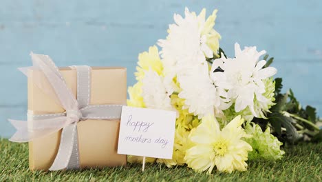 gift box, happy mother day tag and flowers on grass