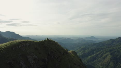 Woman-in-white-dress-stands-on-Little-Adam's-Peak-in-Sri-Lanka,-sunrise