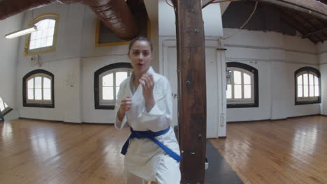 handheld shot of girl in kimono and blue belt punching and kicking at camera