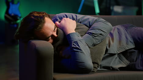 hombre acostado abrazando almohada viendo la televisión, con el corazón roto por la trama de la película perturbadora