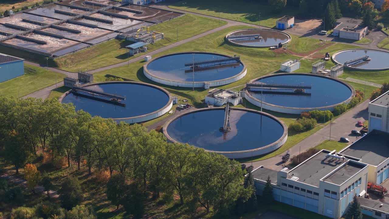Close-up aerial view of a water treatment plant in Kaunas, Lithuania, featuring large circular sedimentation tanks used for wastewater processing and environmental management