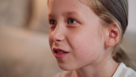 close up of cute child enjoying dinner with sauce on lips while smiling and conversing with someone in background in cozy room setting featuring soft blurred backdrop