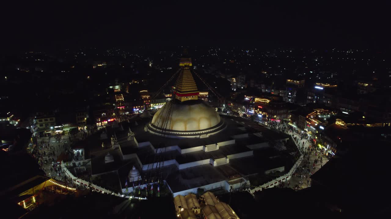 Vista aerea notturna e tranquilla dello stupa di Boudhanath, con Boudha e Nath indicati separatamente, che risplende su Kathmandu. Il sacro punto di riferimento buddista si erge radioso nel tranquillo paesaggio urbano serale.