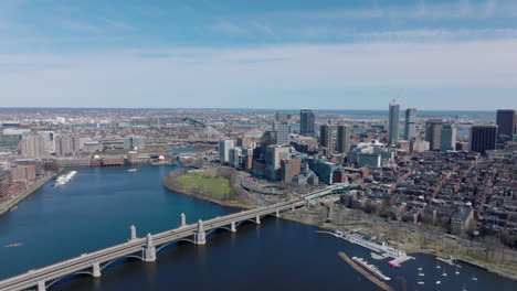 Aerial-panoramic-view-of-Longfellow-Bridge-over-Charles-river,-busy-multilane-road-on-waterfront-and-high-rise-buildings-protruding-above-other-development.-Boston,-USA