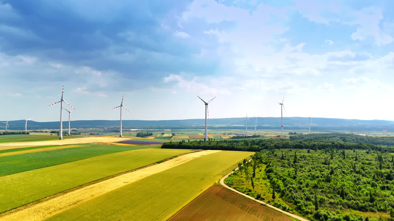 Wind turbines in the countryside. Wind turbines rise above green fields and forests, generating clean energy under a bright blue sky
