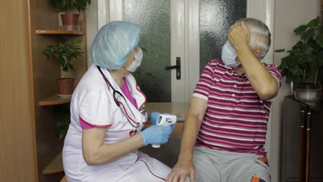 la enfermera mide la temperatura con un termómetro electrónico sin contacto del abuelo enfermo. coronavirus