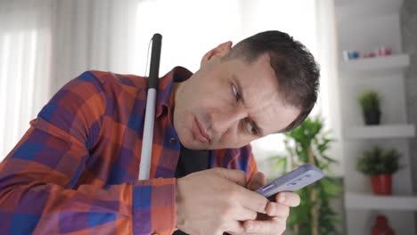 hombre con miopía. puede leer muy de cerca. está mirando el teléfono.