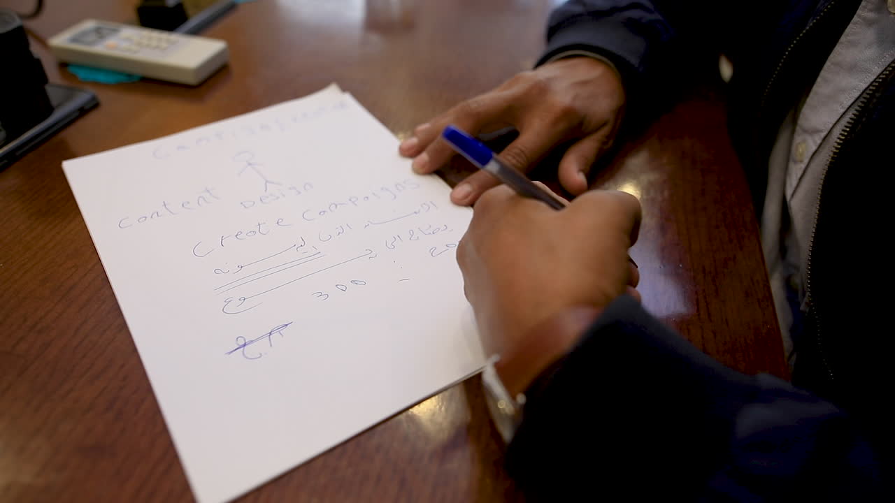 Close-up of the male hands wearing the watch and writing on paper on the table in the office