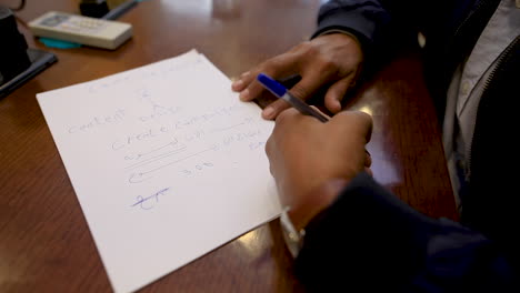 close-up of the male hands wearing the watch and writing on paper on the table in the office