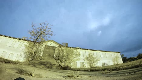 Nachtzeitraffer---Mond-Und-Wolken-Bewegen-Sich-Schnell-Hinter-Einem-Großen-Verlassenen-Gebäude