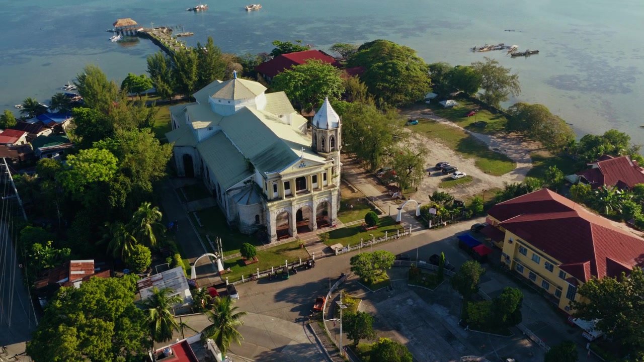 Vista lateral da Igreja de Dauis perto da orla tropical em Bohol, Filipinas, revelada por órbita de drone.