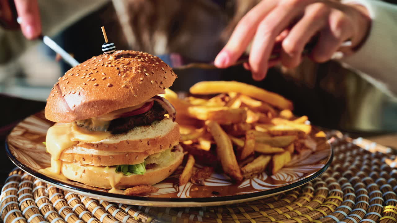 Gourmet burger served on a patterned plate in bright daylight, with blurred restaurant terrace in the background