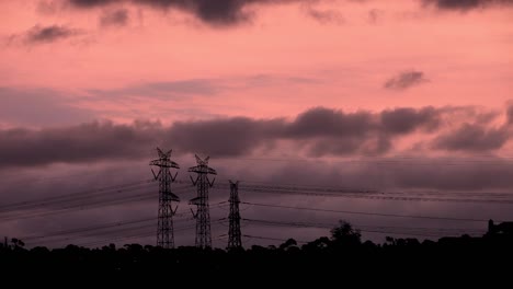 Bright-orange-dusk-sunset-setting-behind-dark-ominous-storm-clouds