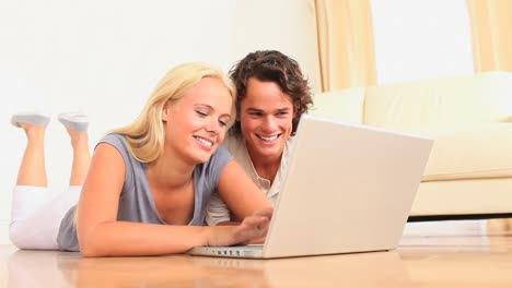 Cute-couple-lying-on-the-floor-with-a-laptop