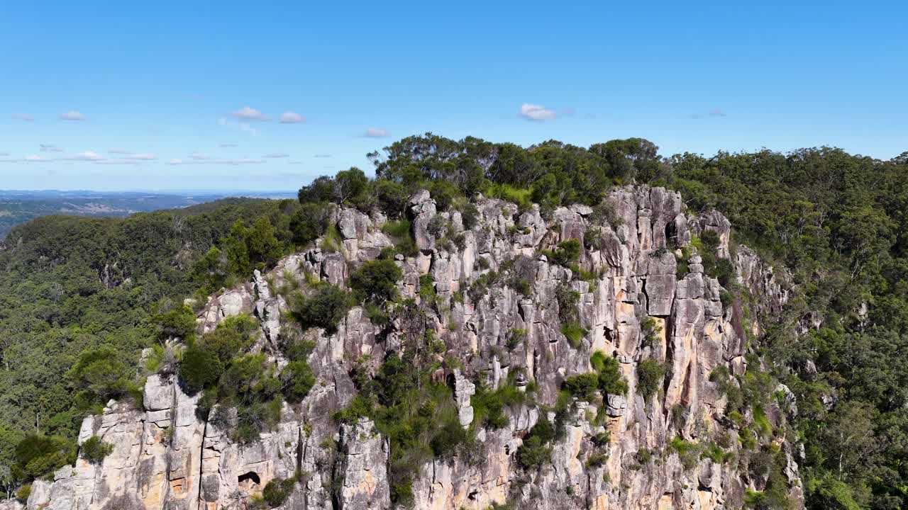 Drone footage captures the rugged beauty of Nimbin Rocks, showcasing lush greenery and striking rock formations under clear blue skies