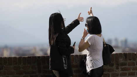 female tourist directing friend for photoshoot with blurry scenic background