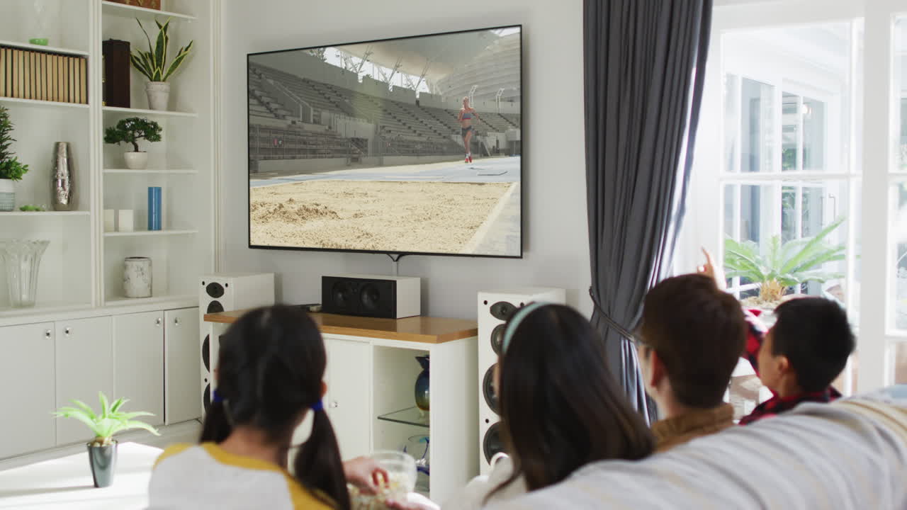 행복 한 가족 이 집 에서 함께 앉아서 tv 에서 장거리 점프 경기를 시청 하고 있다