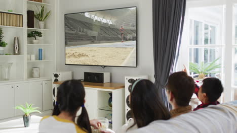 행복 한 가족 이 집 에서 함께 앉아서 tv 에서 장거리 점프 경기를 시청 하고 있다