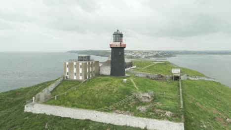 drone passes by the ballycotton lighthouse on a cloudy day in county cork, ireland