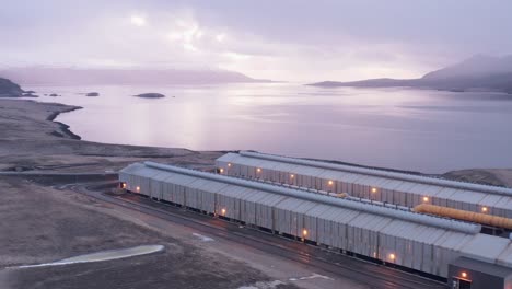 alcoa fjardaál aluminium smelter on shore of fjord with cloudy sunrise, aerial