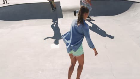 mujer caucásica y dos amigos hombres patinando en un día soleado