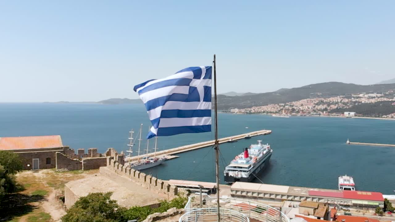 bandera griega ondeando punto aéreo de interés toma de la ciudad de kavala grecia, video en cámara lenta