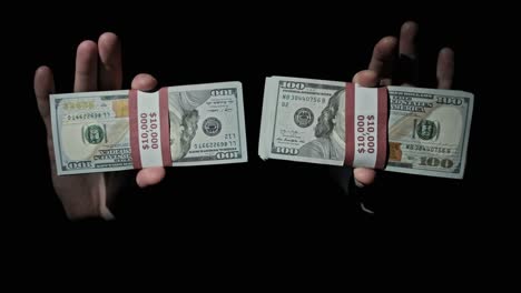 dos pilas de 10000 dólares estadounidenses paquetes en manos masculinas en fondo negro