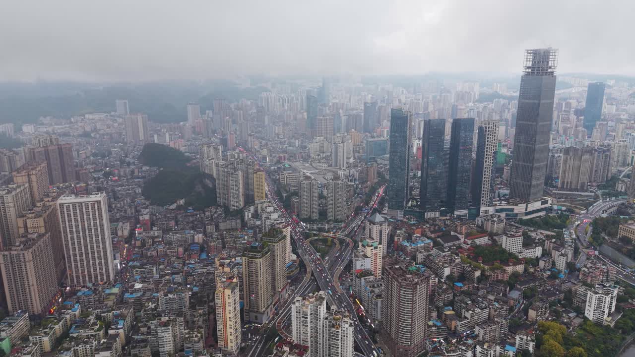 Revealing drone shot of a multi-tiered traffic interchange and highway flyover cutting through the dense cityscape of Guiyang, Guizhou Province