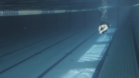 toma submarina de una joven nadadora buceando atléticamente en una piscina