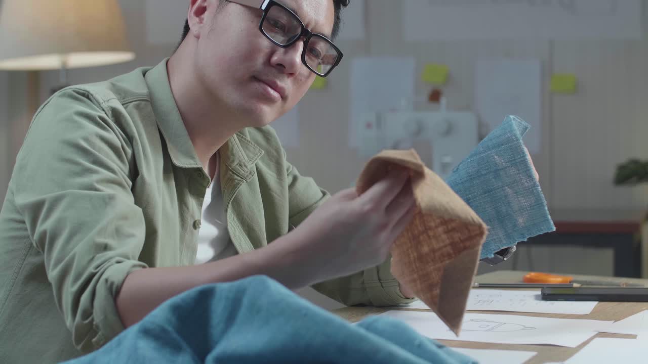 손에 직물을 바라보는 레이아웃 본드와 함께 아시아 남자 디자이너의 클로즈업