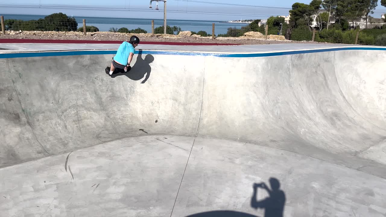 un joven monta una patineta en el tazón de un parque de patinaje