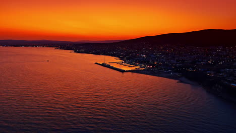 Beautiful sunset over the coastal town. Vibrant sunset colors illuminate the sky as boats rest in the calm water, reflecting the evening glow