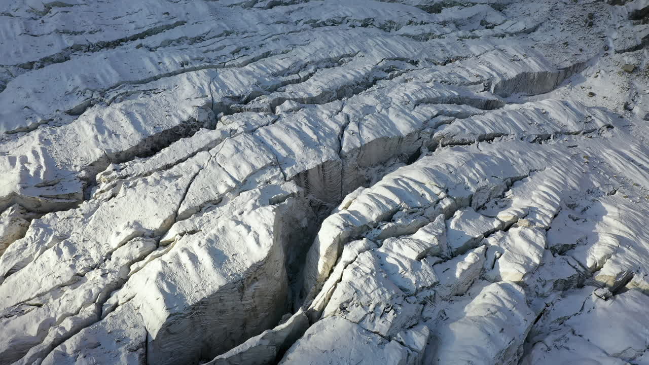 Rotating cinematic aerial drone shot of many crevasses through the Ak-Sai glacier