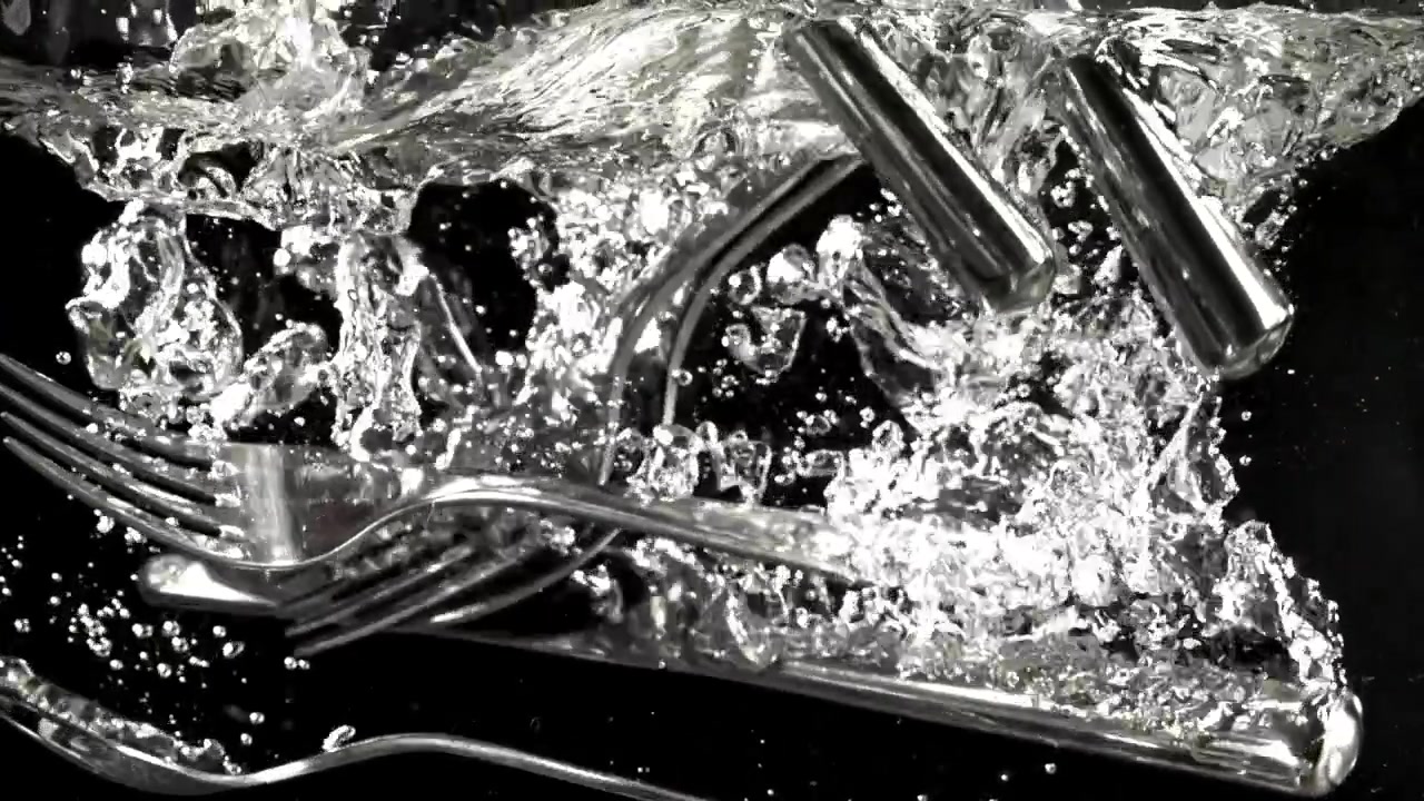 Zeitlupe von Besteck, das mit Blasen ins Wasser fällt