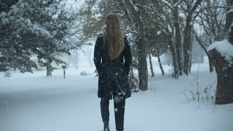 Mujer-Caminando-Afuera-En-Cámara-Lenta,-Nieve-Invernal-Navideña-Mientras-Los-Copos-De-Nieve-Caen-En-Cámara-Lenta-Cinematográfica