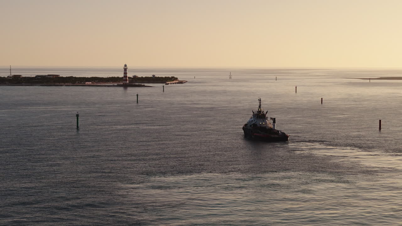 Tugboat navigating a harbor channel at sunset/sunrise