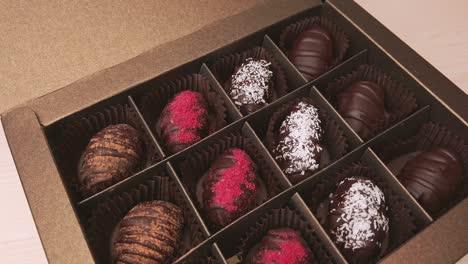 chocolate candies in crafting gift box extreme close up. 4k closeup footage of camera slowly moving between assorted chocolates confectionery on the white background