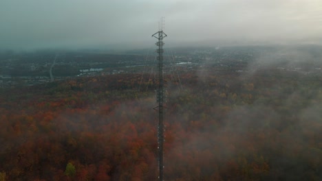 Communications-Tower-Surrounded-By-The-Autumnal-Trees-In-The-Forest-On-A-Foggy-Morning-In-Quebec,-Canada